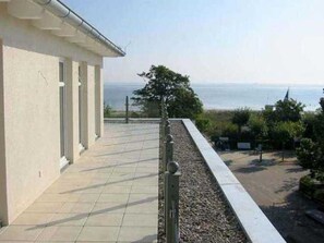 Un bâtiment doté d’un balcon carrelé qui donne sur une étendue d’eau.