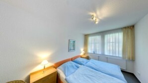 Une chambre d’hôtel avec un lit, des tables de chevet, une fenêtre avec des rideaux et un tableau accroché au mur.