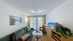 Un salon avec un canapé, une table basse en verre, un téléviseur et une plante.