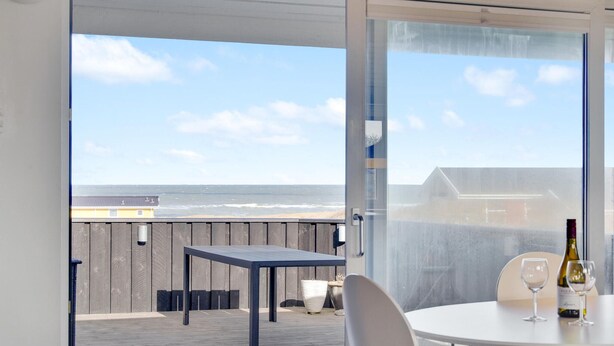 A balcony with a table and chairs, a bottle of wine, and a glass. - 2 bedroom amazing home in Hjørring (Hjørring)