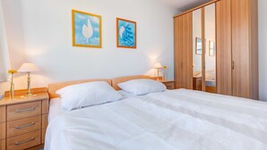 A bedroom with a bed, two bedside tables with lamps, a wardrobe, and two framed pictures on the wall. - Villa Aquamarina Whg. 15, BALCONY, CHAIR - Villa Aquamarina, 1st FLOOR, partly. (Heringsdorf)