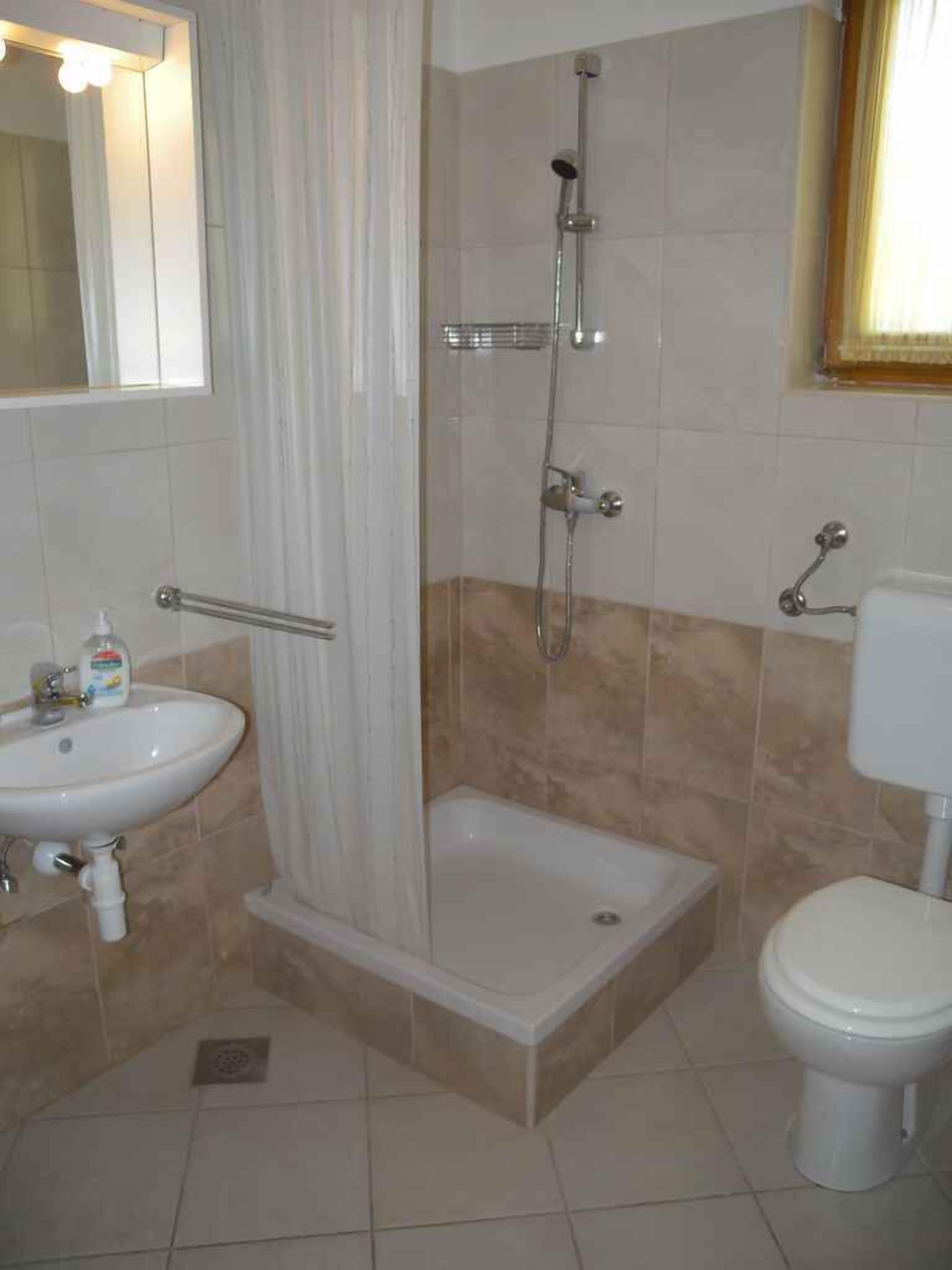 A bathroom with a shower, sink, and toilet.