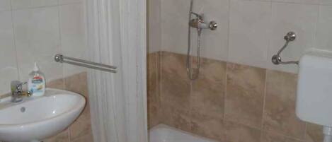A bathroom with a shower, sink, and toilet.