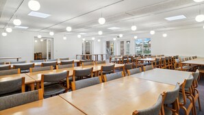 Ett rymligt matområde med flera bord och stolar, stora fönster och en stilren, modern design.