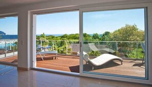 A spacious balcony with a wooden deck, a lounge chair, and a view of greenery and a building in the distance. - Beletage 3 - Villa Ostseeblick 5 * with sea and Boddenblick (Göhren)