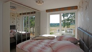 Une chambre avec un grand lit, une armoire et une porte-fenêtre coulissante donnant sur un balcon.