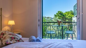 Une chambre d’hôtel avec un lit, une table de chevet avec une lampe et un balcon avec deux chaises et une table.