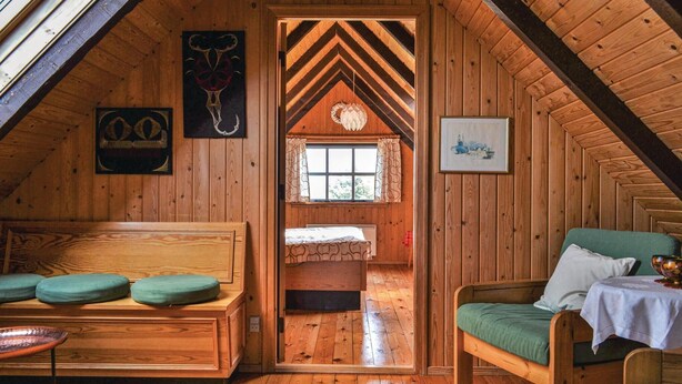 A cozy attic room with wooden walls, a loft bed, a green sofa, and a small table. - 3 bedroom amazing home in Hvide Sande (Hvide Sande)