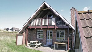 A two-story house with a balcony, a front door, and a small porch with a bench. - 3 bedroom amazing home in Hvide Sande (Hvide Sande)