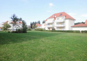 A residential area with a grassy lawn, a small tree, and a multi-story building with balconies. - Kiebitz 8 - between the Baltic Sea and shopping - Apartment Kiebitz 8 (Graal-Müritz)