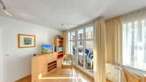 A bright room with a wooden cabinet, a television, and a chair.