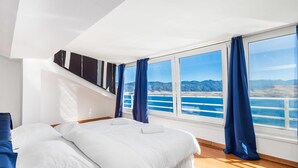 A modern bedroom with a large bed, a view of a body of water, and a mountain landscape. - 5 bedroom awesome home in Pag (Pag)