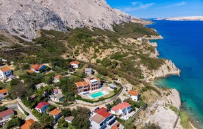 Une zone résidentielle côtière avec des maisons, une piscine et une falaise rocheuse.