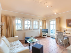 Ein Wohnzimmer mit einer Couch, einem Couchtisch, einem Fernseher und einem Essbereich mit einem Stuhl und Tisch.
