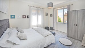 Een slaapkamer met een groot bed, een garderobe en een raam met uitzicht op gebouwen.