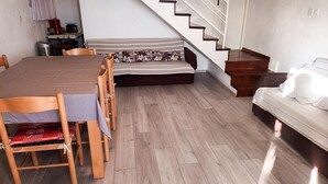 A dining area with a wooden table and chairs, a sofa with patterned cushions, and a staircase leading to another level. - Pet friendly home in Baric Draga with WiFi (Baric Draga)