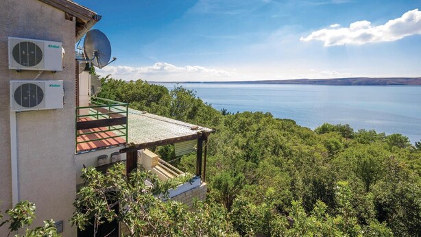 A building with air conditioning units, a balcony with a view of a lake, and lush greenery. - Pet friendly home in Baric Draga with WiFi (Baric Draga)