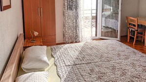 A bedroom with a bed, a wooden wardrobe, a desk with a chair, and a sliding glass door leading to an outdoor area. - Pet friendly home in Baric Draga with WiFi (Baric Draga)