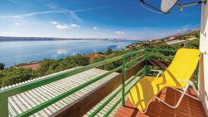 A balcony with a yellow chair, a satellite dish, and a view of a calm lake with houses in the background. - Pet friendly home in Baric Draga with WiFi (Baric Draga)