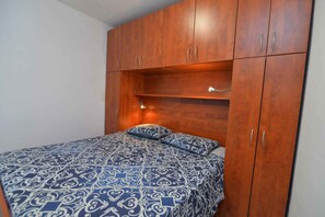 Een slaapkamer met een bed, een houten kledingkast en een plankunit.
