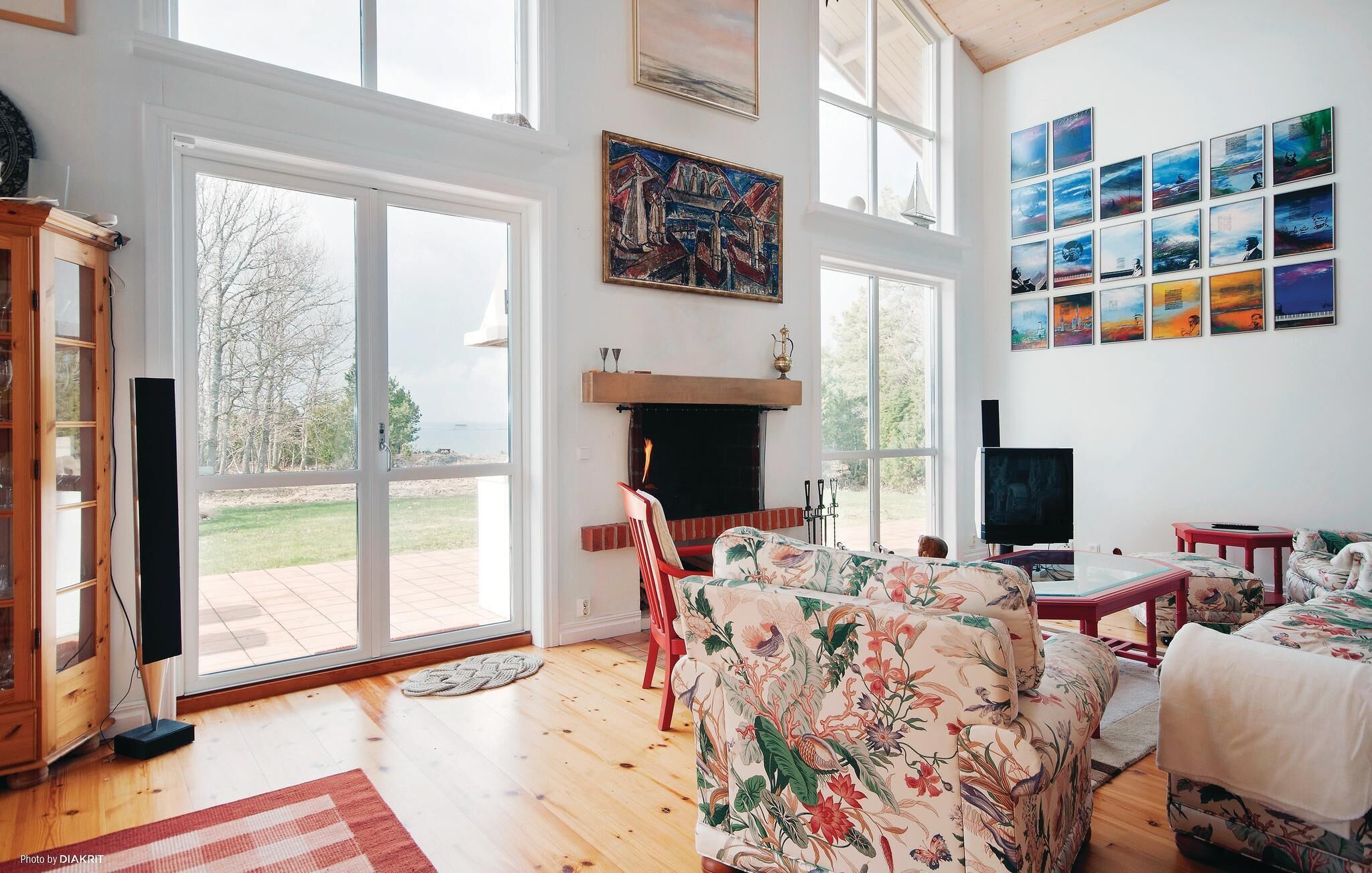 Un salón comedor amplio con chimenea, ventanas grandes y una colección de obras de arte en las paredes.