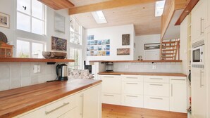 Una cocina amplia con encimeras de madera, armarios blancos y un tragaluz.