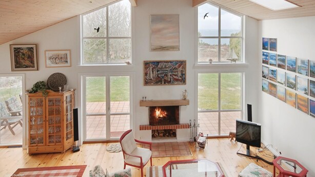 Un salón amplio con chimenea, ventanas grandes y una colección de obras de arte en las paredes.