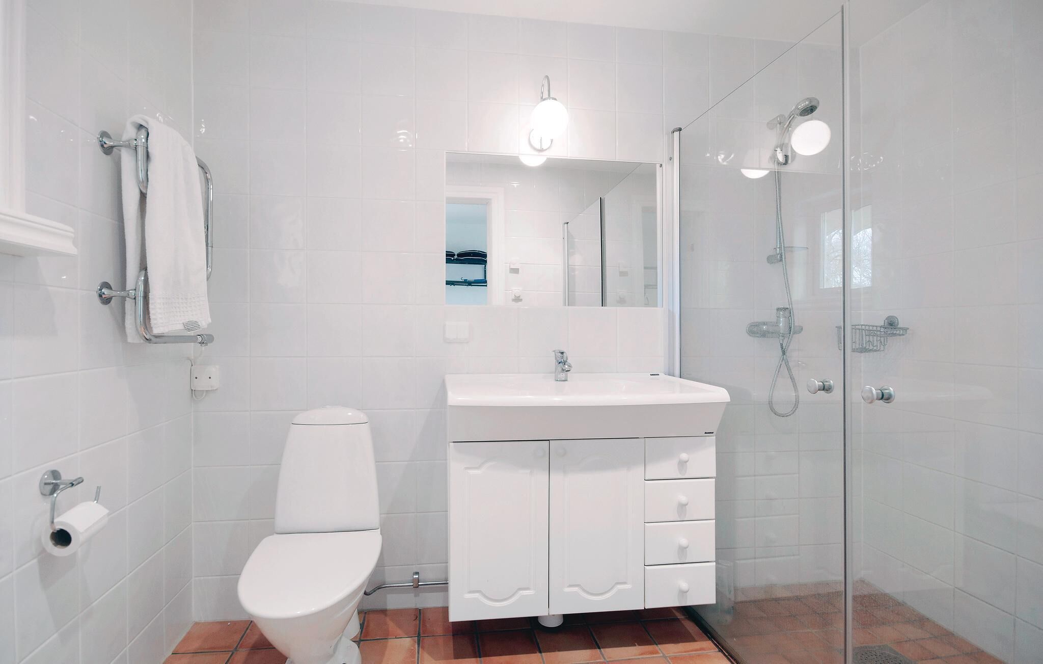 A modern bathroom with a toilet, sink, and glass shower enclosure.