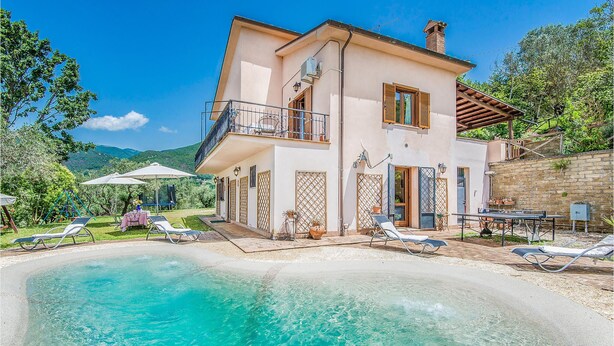 A two-story house with a swimming pool, outdoor furniture, and a garden.