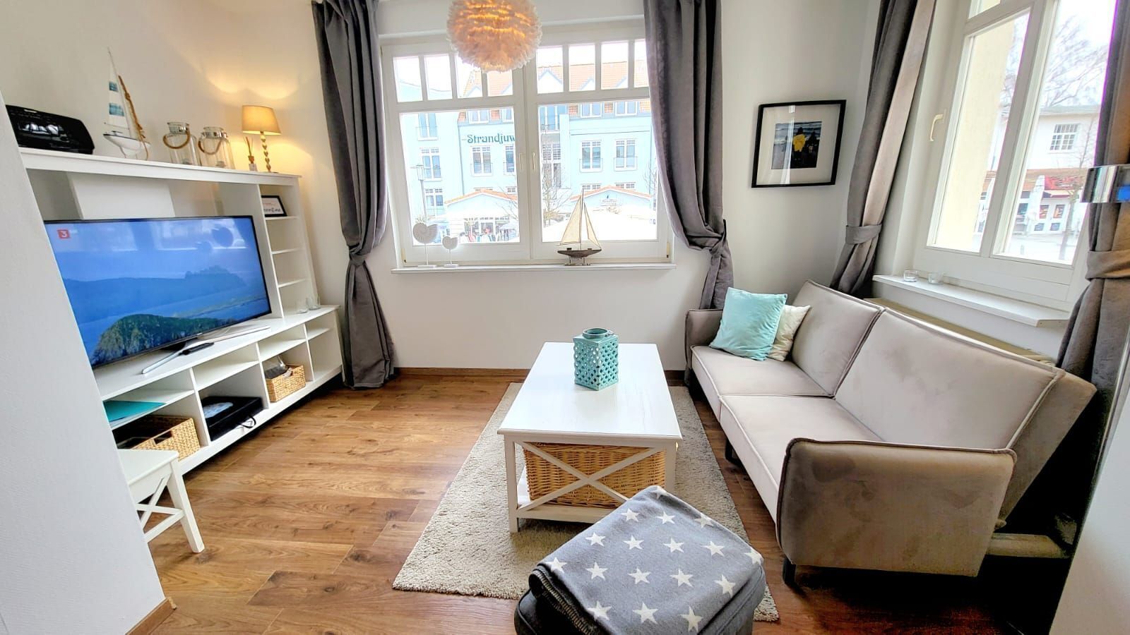 A living room with a television, sofa, coffee table, and a view of buildings outside.