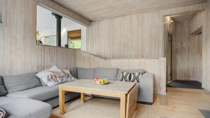 A modern living room with a wooden floor, grey sofas, a wooden coffee table with fruit, and a large window. - Nice home in Ebeltoft with kitchen (Ebeltoft)