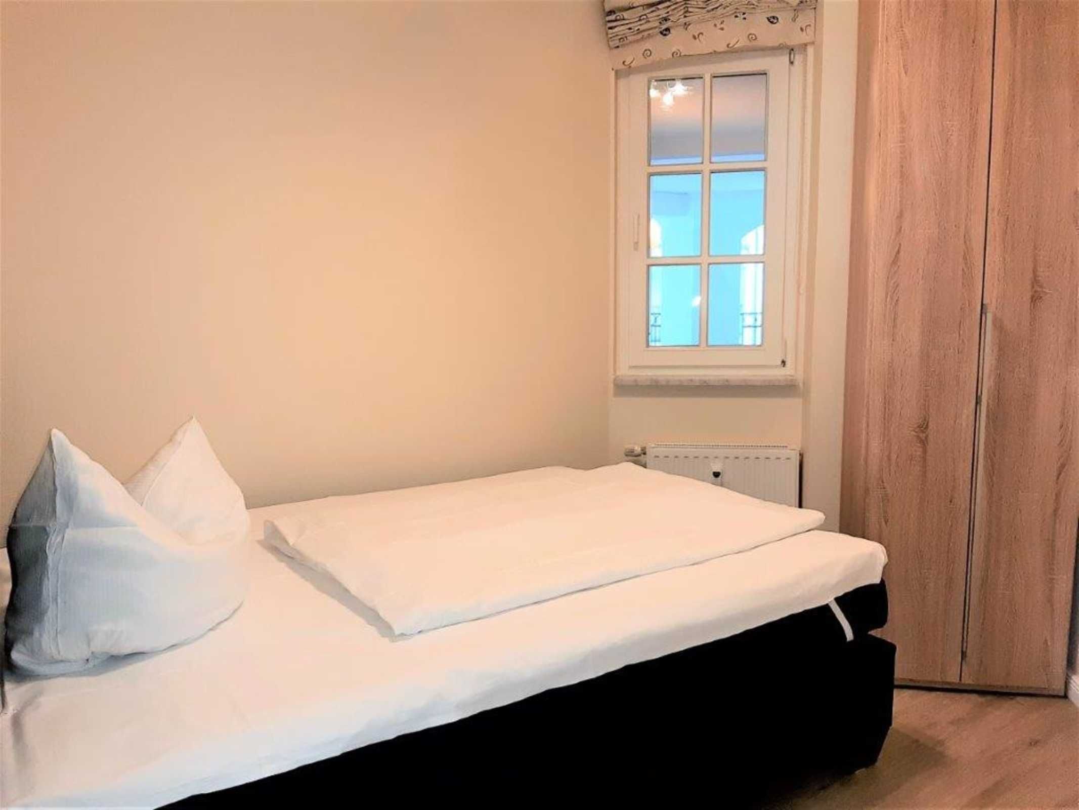 A bedroom with a bed, a window, and a wardrobe.