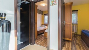 Une pièce avec un lit, un plancher en bois, une porte et une fenêtre.