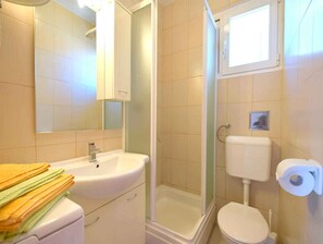 Ein Badezimmer mit Waschbecken, Spiegel, Toilette und Dusche.