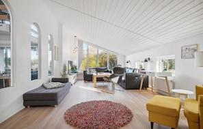 A spacious living room with a large window, a grey sofa, a yellow armchair, and a wooden coffee table. - Gorgeous home in Thisted with sauna (Thisted)