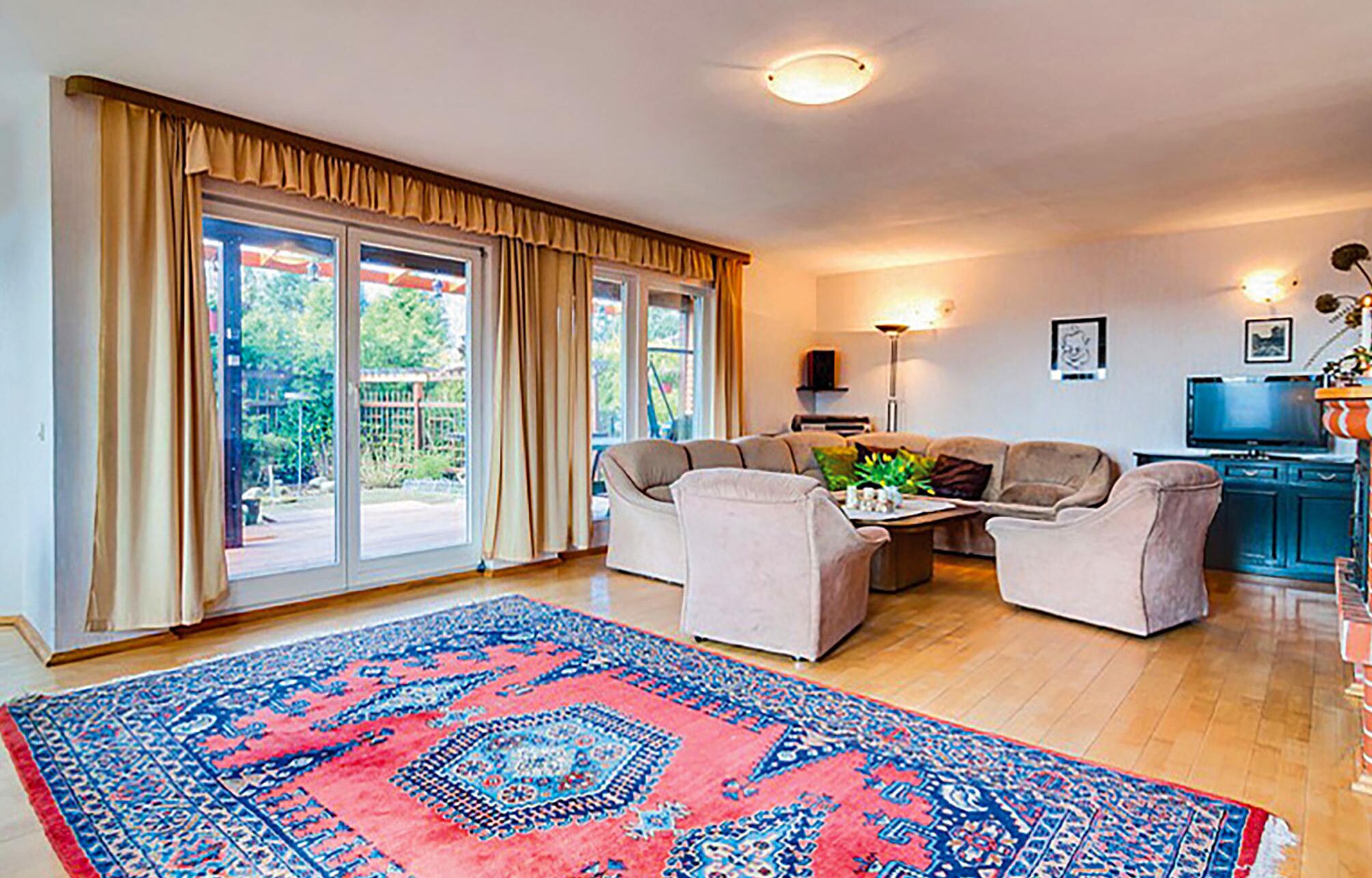 A living room with a large window, a sofa set, a coffee table, and a TV.