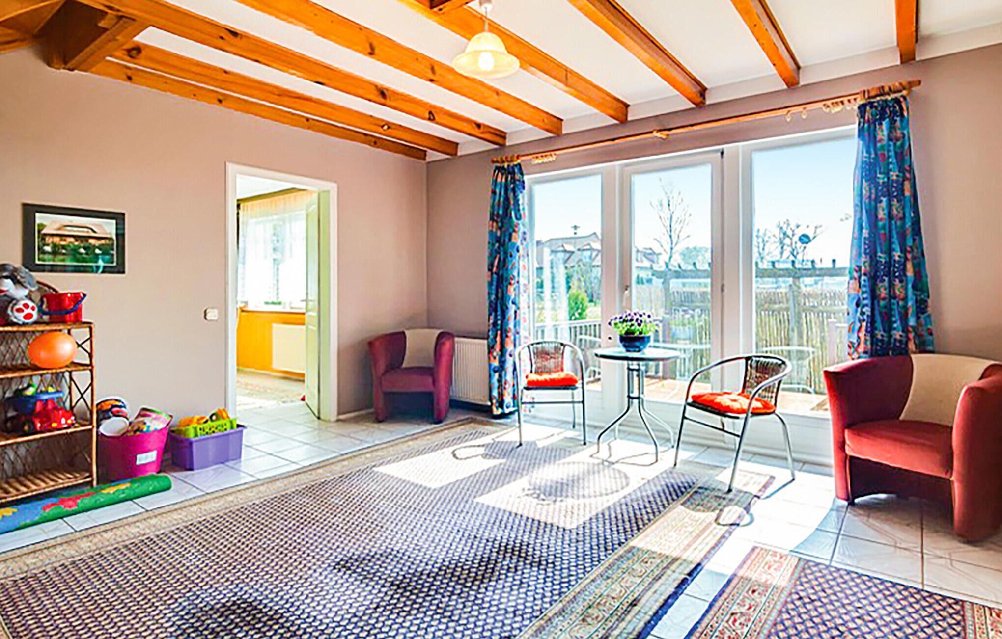 A spacious living room with a high ceiling, large windows, and a view of the outdoors.