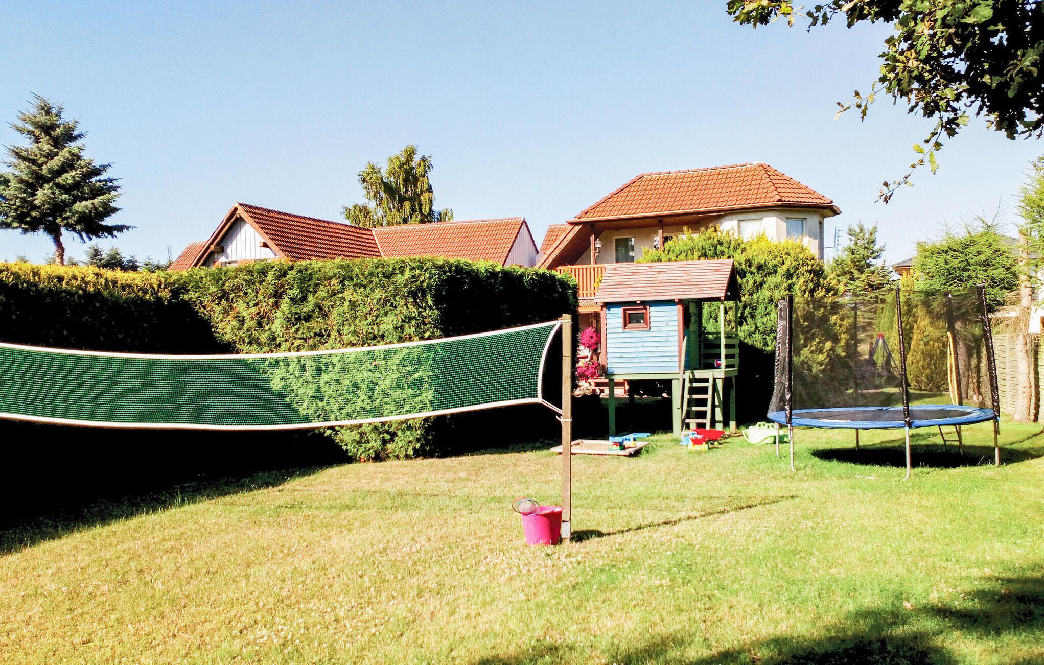A backyard with a trampoline, a playhouse, and a hammock.