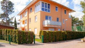 Un immeuble résidentiel à plusieurs étages, doté d’un toit plat, de grandes fenêtres et d’un balcon situé à l’étage supérieur.