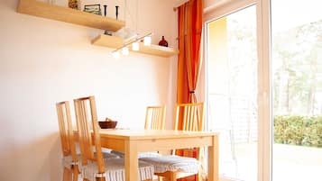 Ein Essbereich mit Holztisch und -stühlen, einer Hängelampe und Blick durch ein großes Fenster.