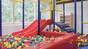 Espaço de recreação infantil com escorregadores, piscina de bolinhas e estrutura de escalada.