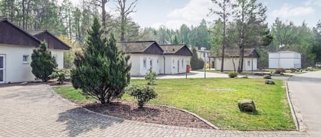 A residential area with detached houses, a paved driveway, and a well-maintained lawn.