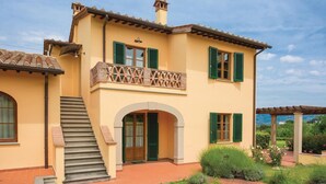 Une maison à deux étages avec un balcon, un escalier et un jardin.