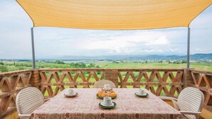Une table dressée pour deux personnes, avec vue sur un paysage verdoyant, à l’abri sous une voûte végétale.