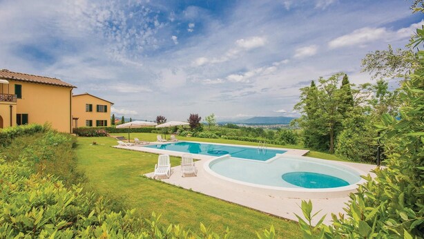 Un espace piscine comprenant deux piscines, une pelouse et un bâtiment doté d’un balcon.
