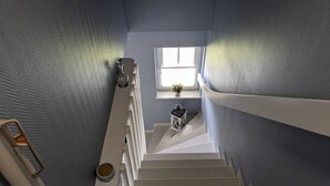 Eine Treppe mit Blick auf ein kleines Fenster und eine Pflanze im Vorraum.