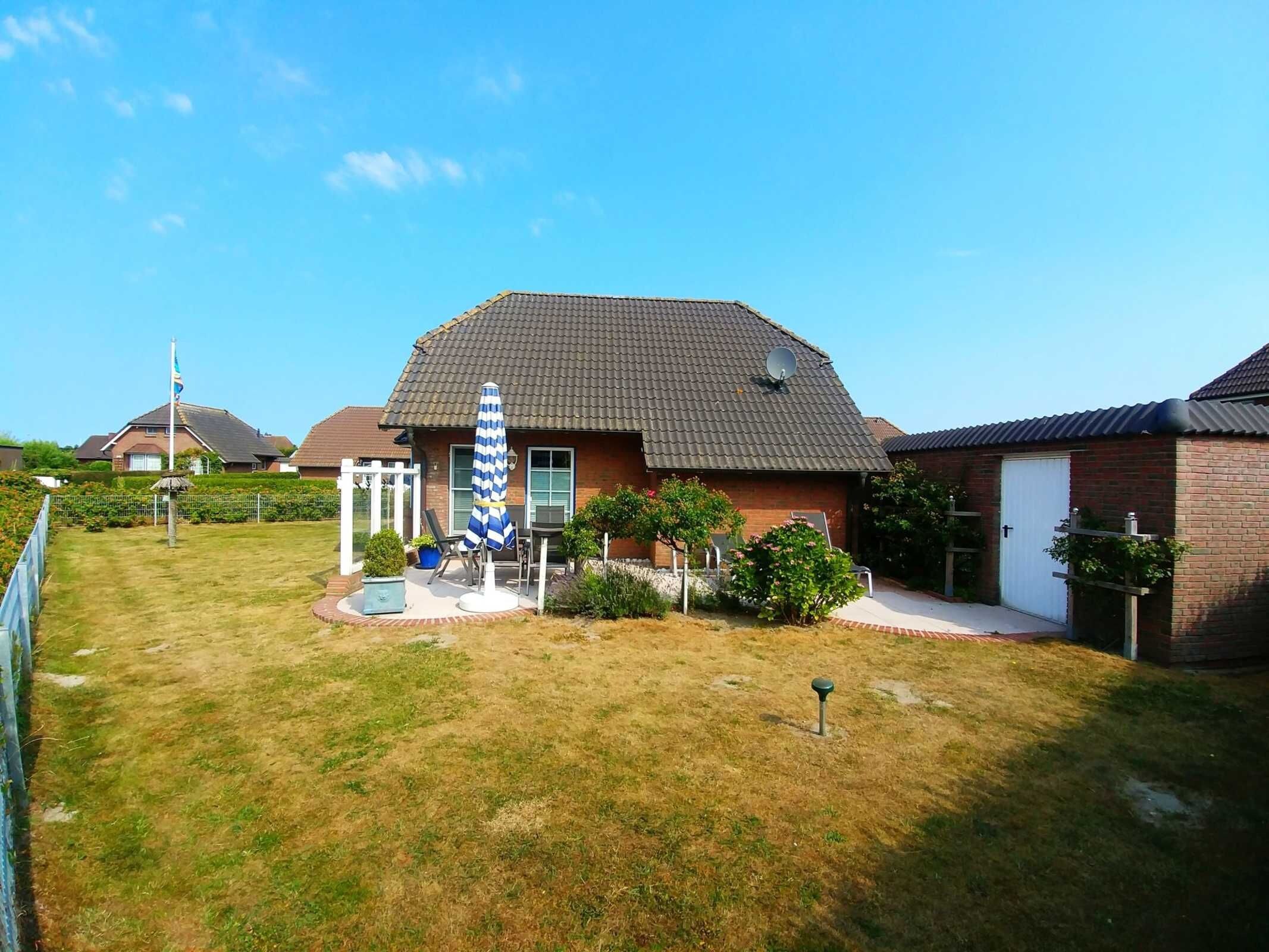 A residential house with a tiled roof, a satellite dish, and a small garden area with a lawn and a blue and white striped umbrella.