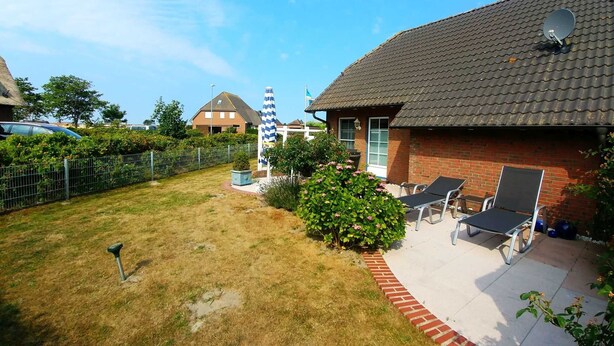 Ein Garten mit Rasen, einer Satellitenschüssel und einem Ziegelhaus mit Ziegeldach.