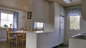 Eine kleine Küche mit Holzschränken, einem Esstisch mit Stühlen und einem Kühlschrank.