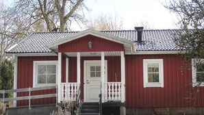 Ein rotes Holzhaus mit einer weißen Veranda und einer Tür.